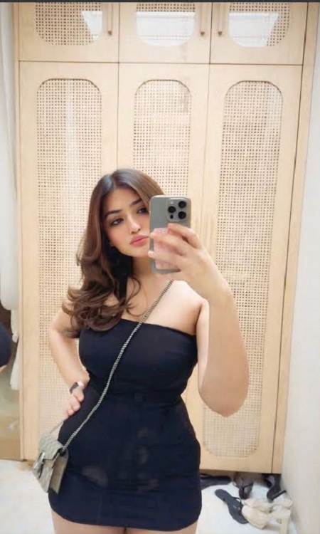 woman in a trendy short dress poses for a selfie, radiating confidence and style in a casual setting.